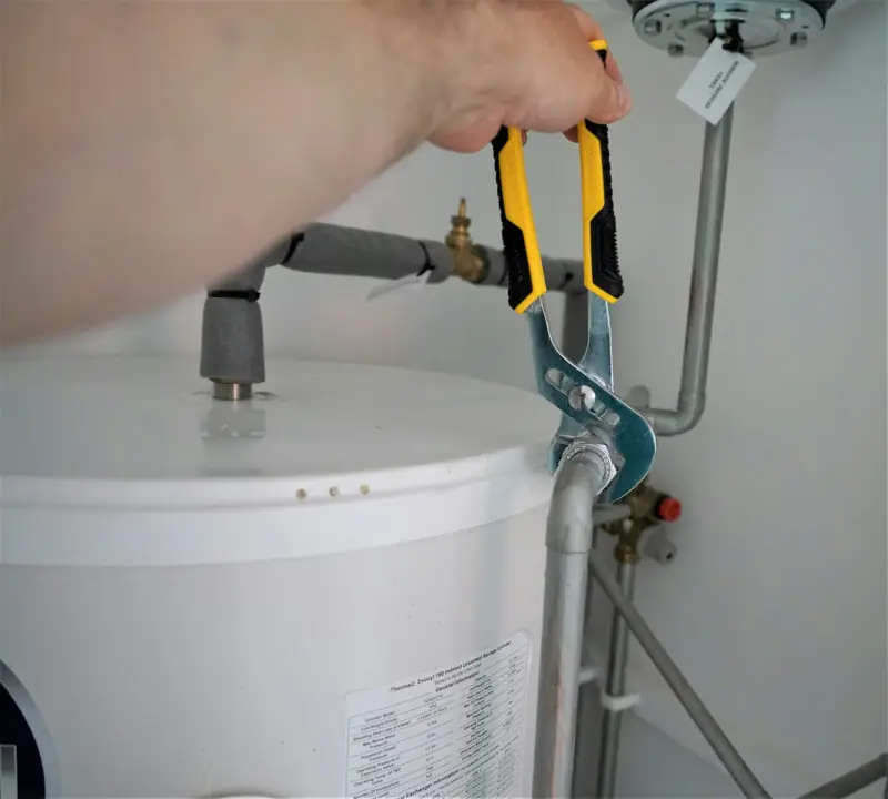 Handwerker zieht eine Verschraubung an einem Warmwasserspeicher fest